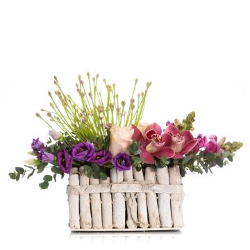 Floral arrangement in basket with roses and purple lisianthus