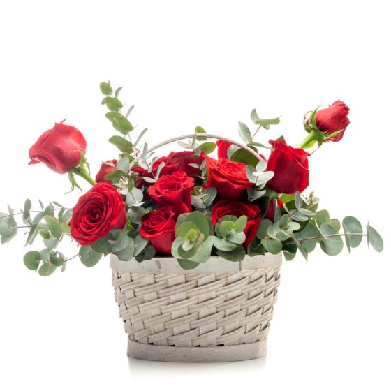 Floral arrangement in basket from red roses, ruscus