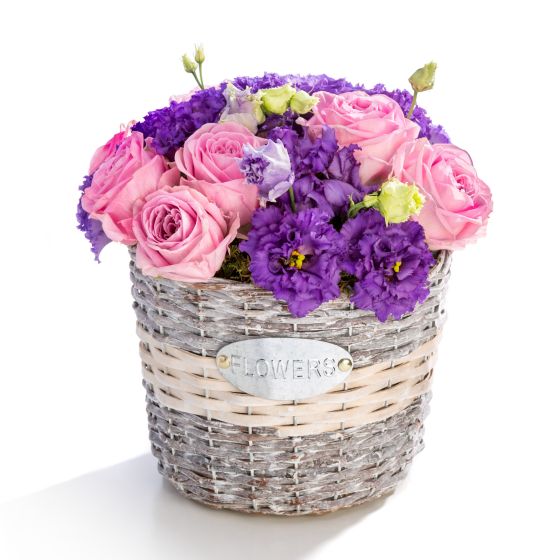 Floral arrangement in basket of pink roses, purple lisianthus