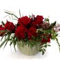 Floral arrangement in ceramic vase with red roses and skimmia