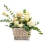 Floral arrangement in basket made of white roses, ruscus